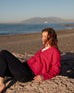 woman wearing hibiscus red buttoned mersea cruiser cardigan on a beach