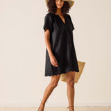 Woman wearing a black dress and straw hat on a plain background