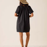 Person wearing a black dress and straw hat on a plain background