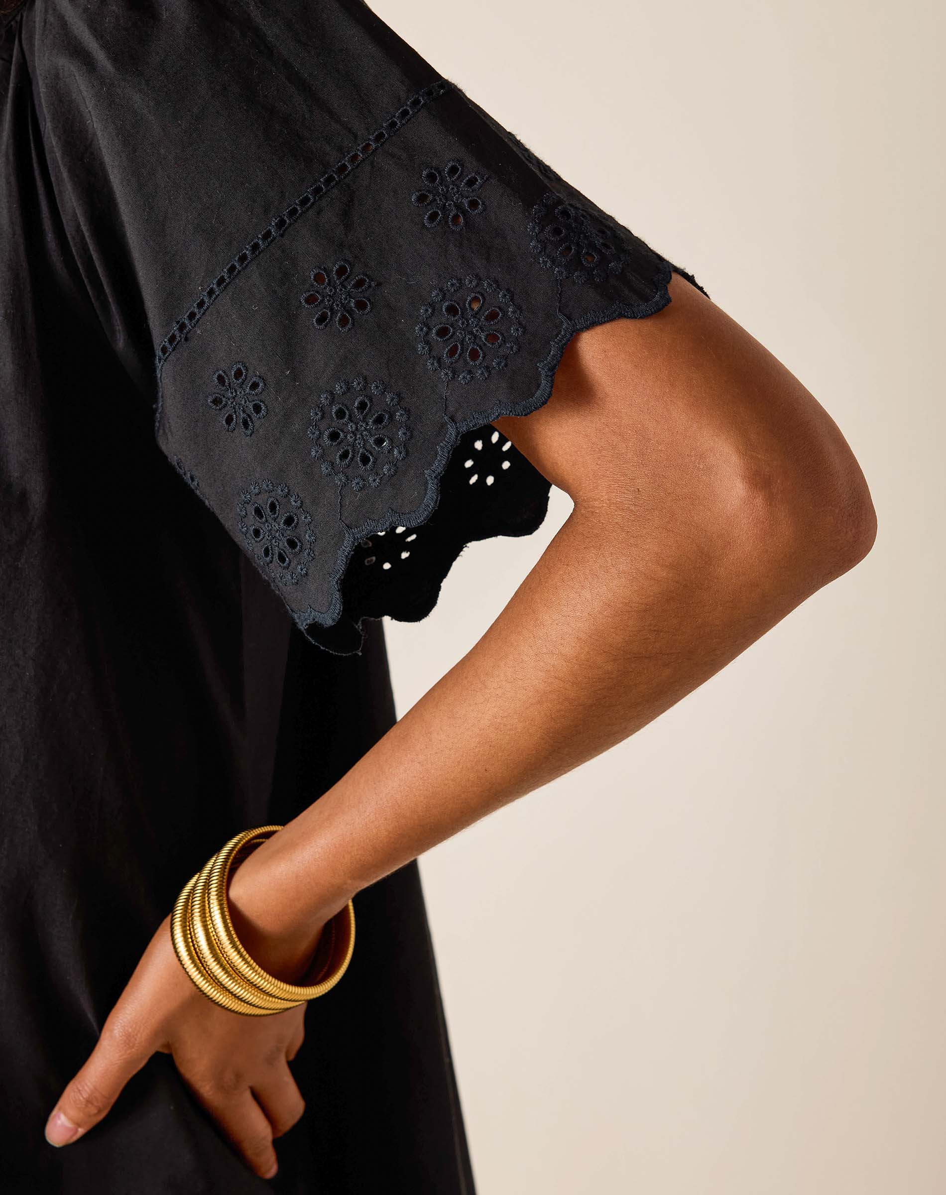 Black dress with floral cut-out details on a beige background