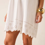 White dress with lace details worn by a person on a beige background