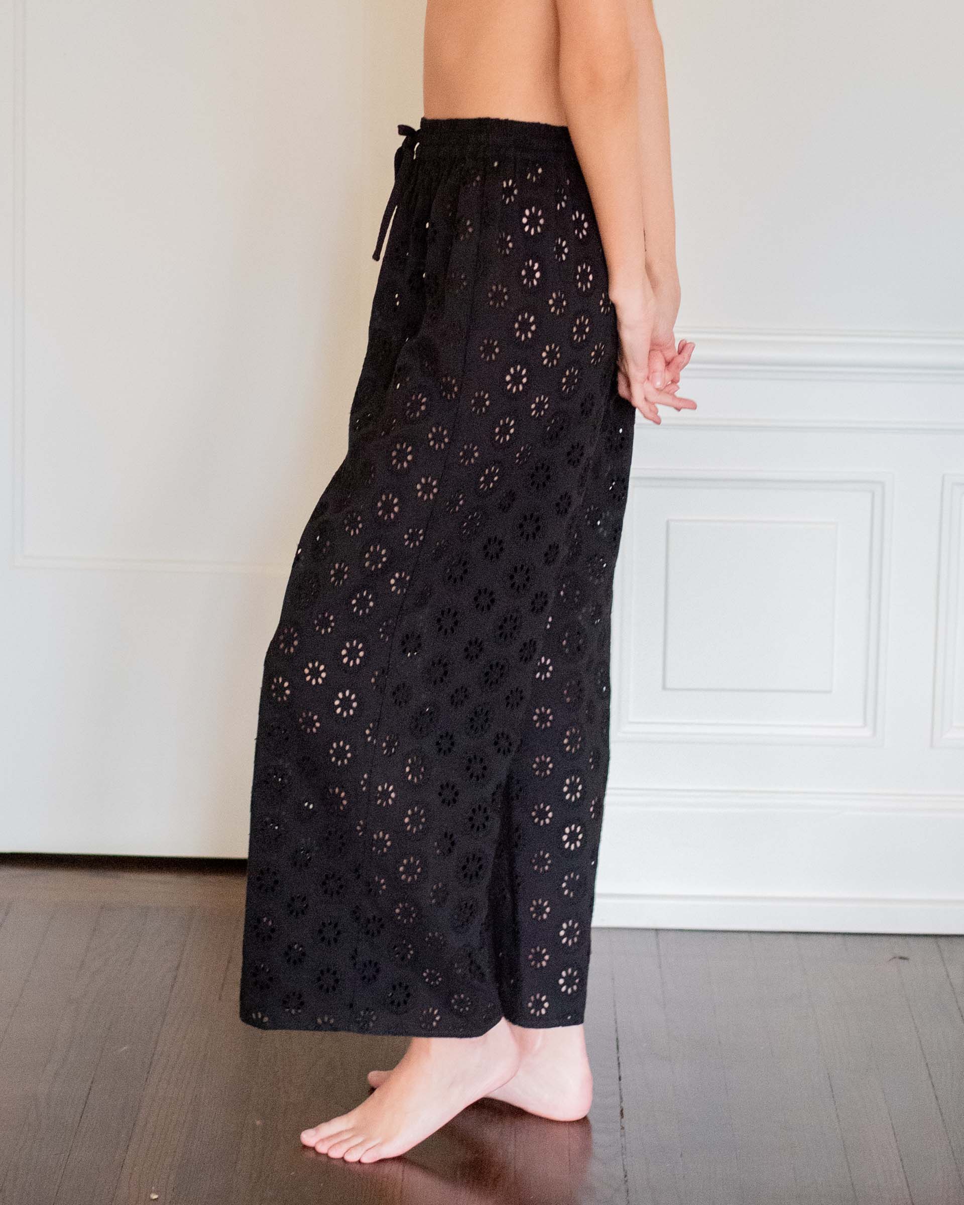side view of woman wearing daisy eyelet pant in black