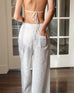 rear view of woman wearing daisy eyelet pant in white with hand in back pocket