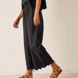 Person wearing black pants and brown sandals on a plain background