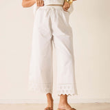 Person wearing a white outfit with embroidered details on a plain background