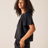 Person wearing a black outfit with intricate details on a plain background