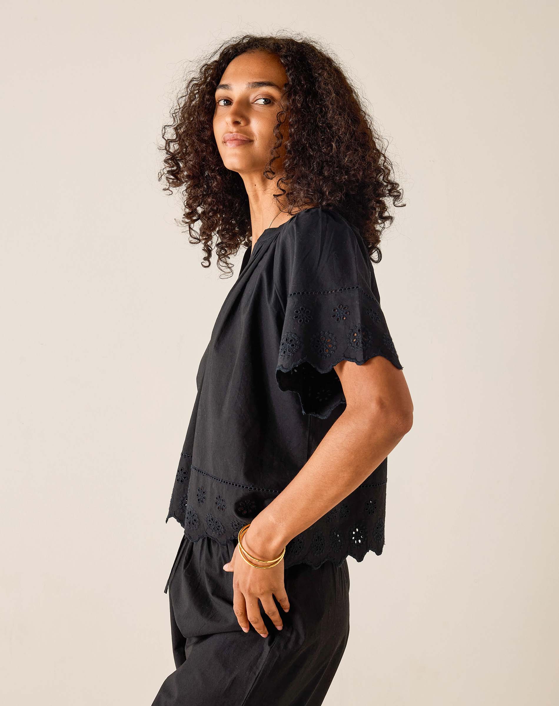 Person wearing a black outfit with intricate details on a plain background