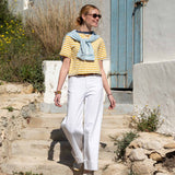MERSEA women's travel-friendly women's travel-friendly golden rod and indigo striped ringer tee paired with white high-waisted wide-leg pants.