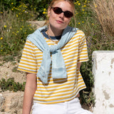 Golden rod and indigo striped ringer tee with a denim jacket draped over the shoulders.