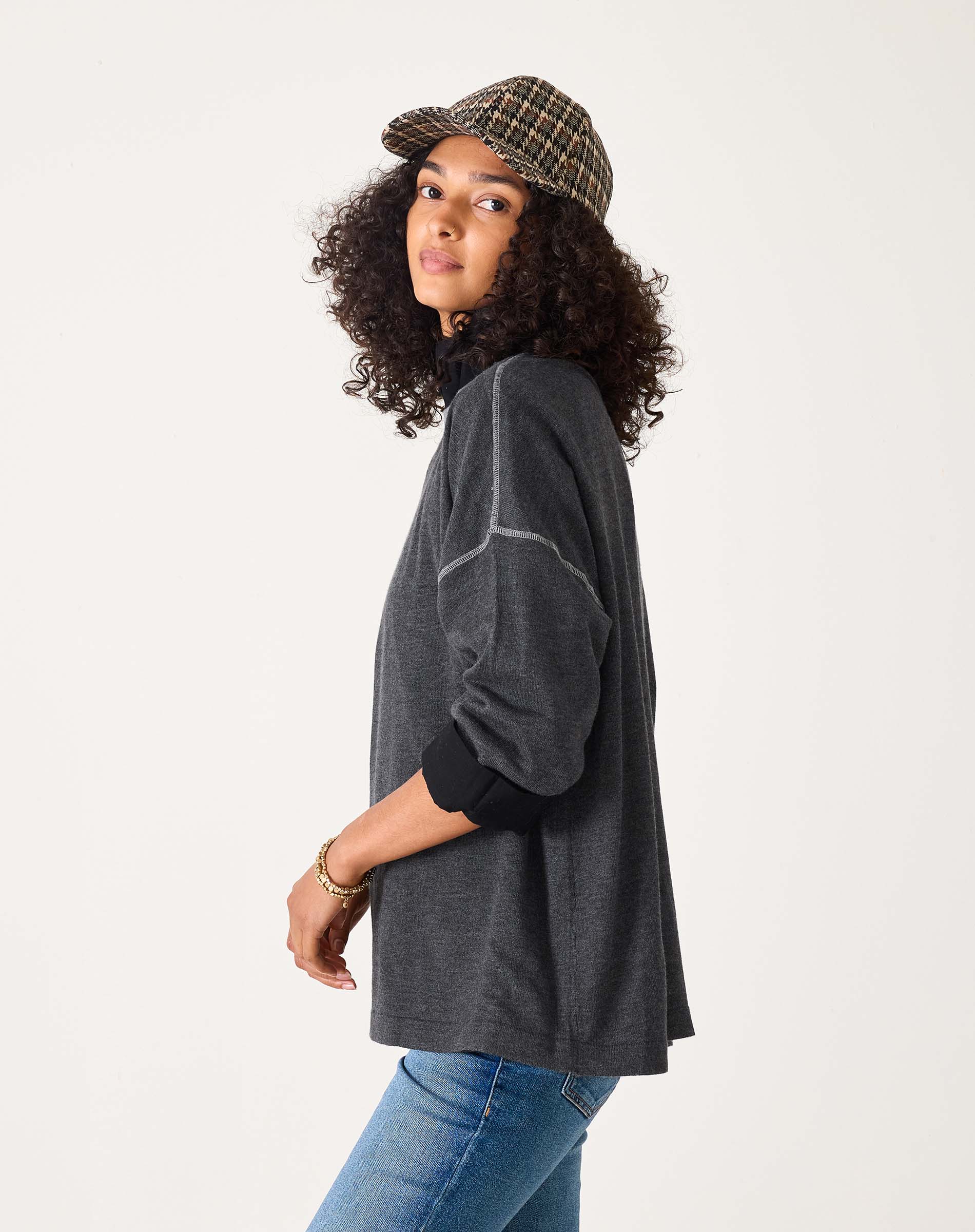 Woman wearing a dark gray sweater and plaid cap on a white background