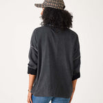 Person wearing a dark gray long-sleeve shirt and blue jeans with a plaid cap on a white background