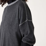 Person wearing a dark gray sweater with black sleeves on a white background