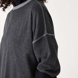 Person wearing a dark gray sweater with black sleeves on a white background