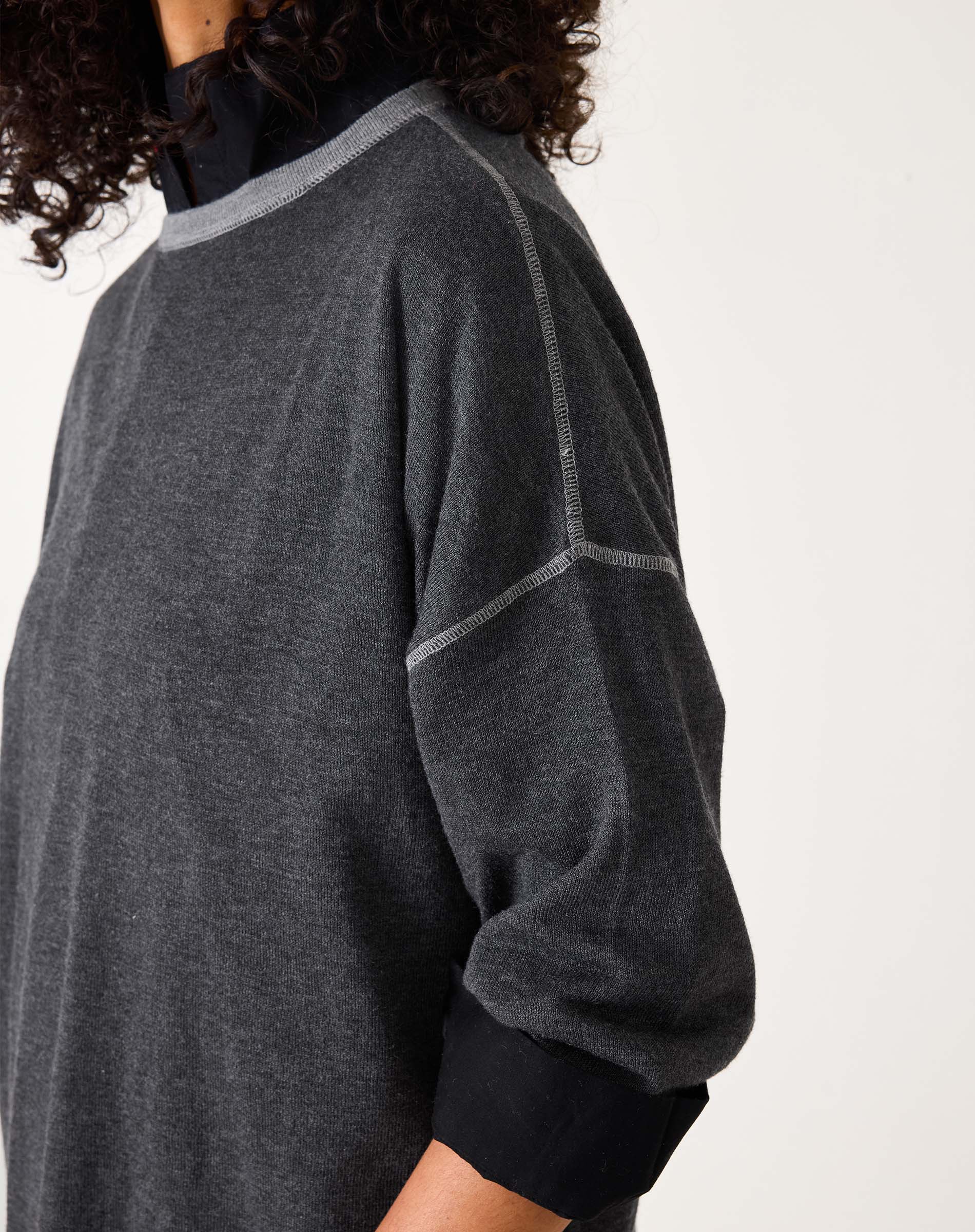 Person wearing a dark gray sweater with black sleeves on a white background