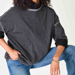 Person wearing a dark gray sweater and blue jeans on a white background