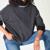Person wearing a dark gray sweater and blue jeans on a white background