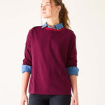Woman wearing a burgundy sweater with denim collar and cuffs on a white background