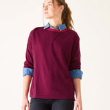 Woman wearing a burgundy sweater with denim collar and cuffs on a white background