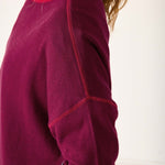 Close-up of a maroon fleece jacket with red stitching on a white background