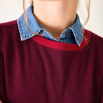 Person wearing a red sweater with a blue collar against a neutral background