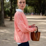 Woman in a pink jacket holding a brown bag outdoors