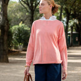 Woman wearing a pink sweater and blue pants outdoors