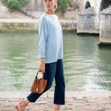 Woman walking by a river with a bridge in the background