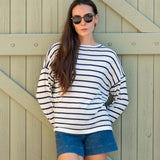 Woman wearing a striped sweater and denim shorts against a wooden background