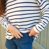 Person wearing a white and navy striped shirt with blue shorts against a neutral background