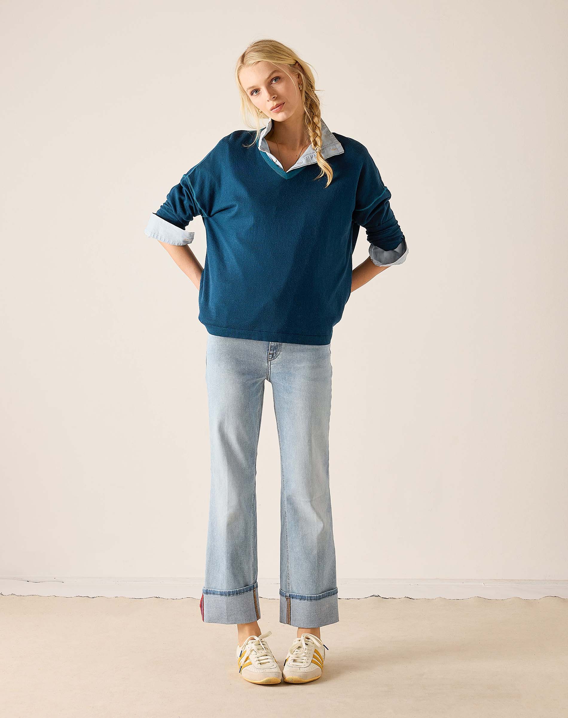 MERSEA ladies' travel-ready deep teal v-neck knit top with a white striped collar and wide-leg jeans.