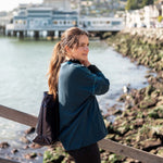 Woman standing by a waterfront with a scenic background