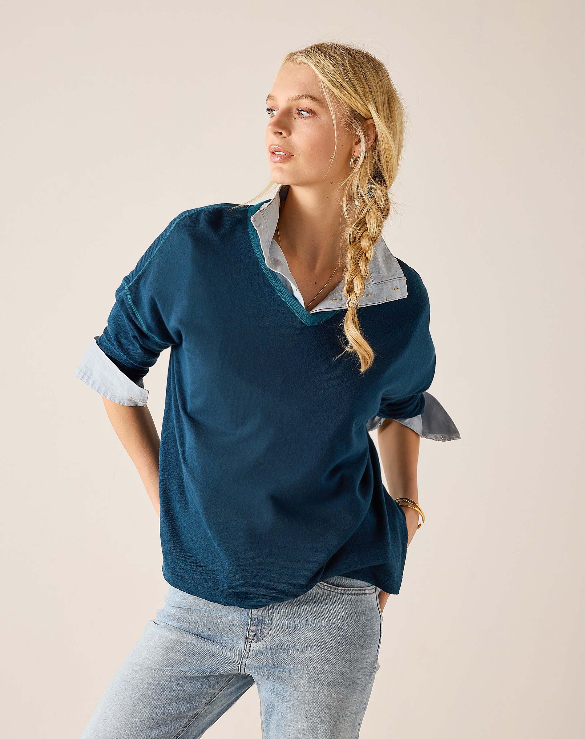 Deep teal v-neck knit top with flared sleeves and a light blue collared shirt underneath