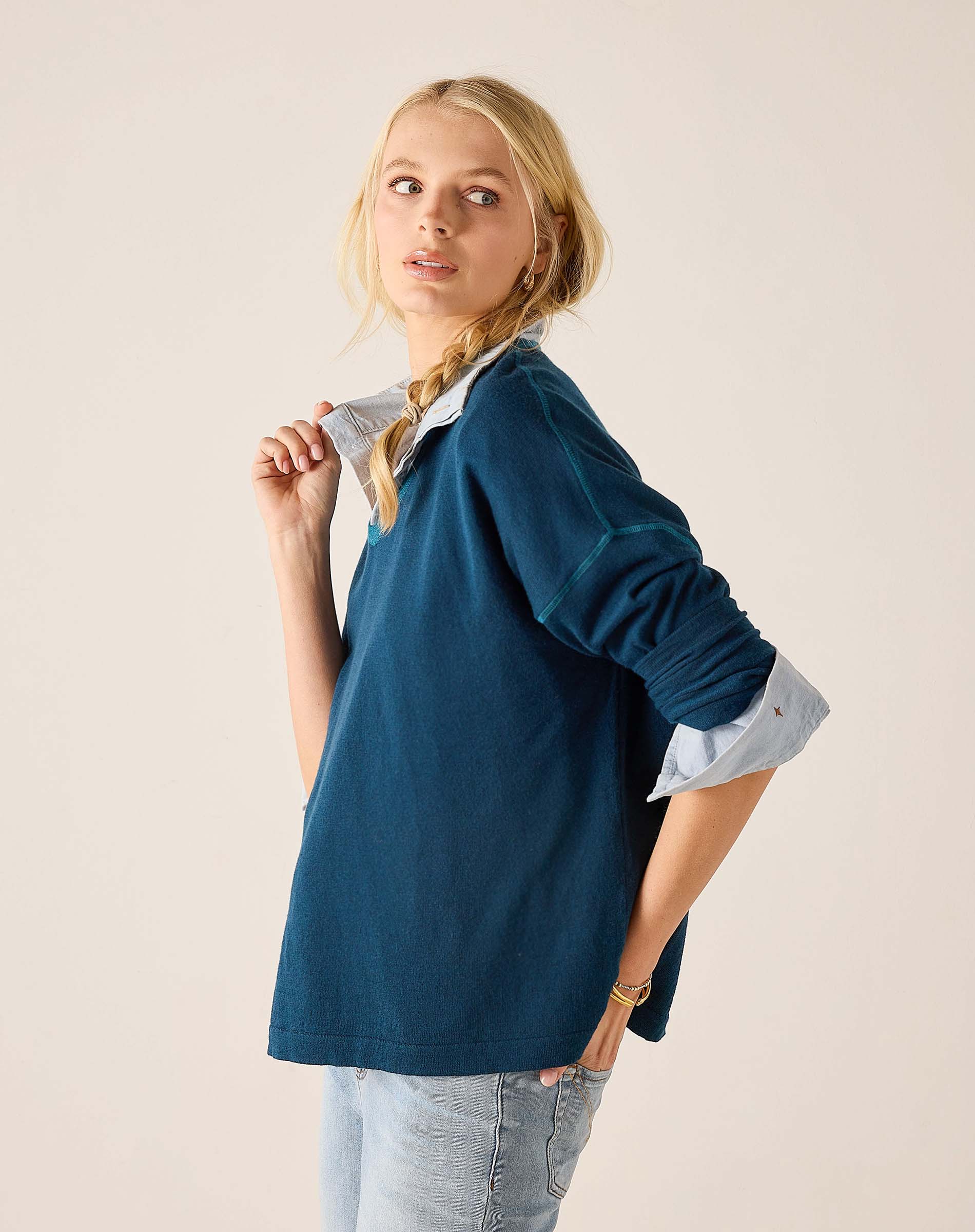 Deep teal v-neck knit top with a layered shirt detail and long sleeves.