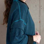 Person wearing a teal fleece jacket with black accents against a neutral background