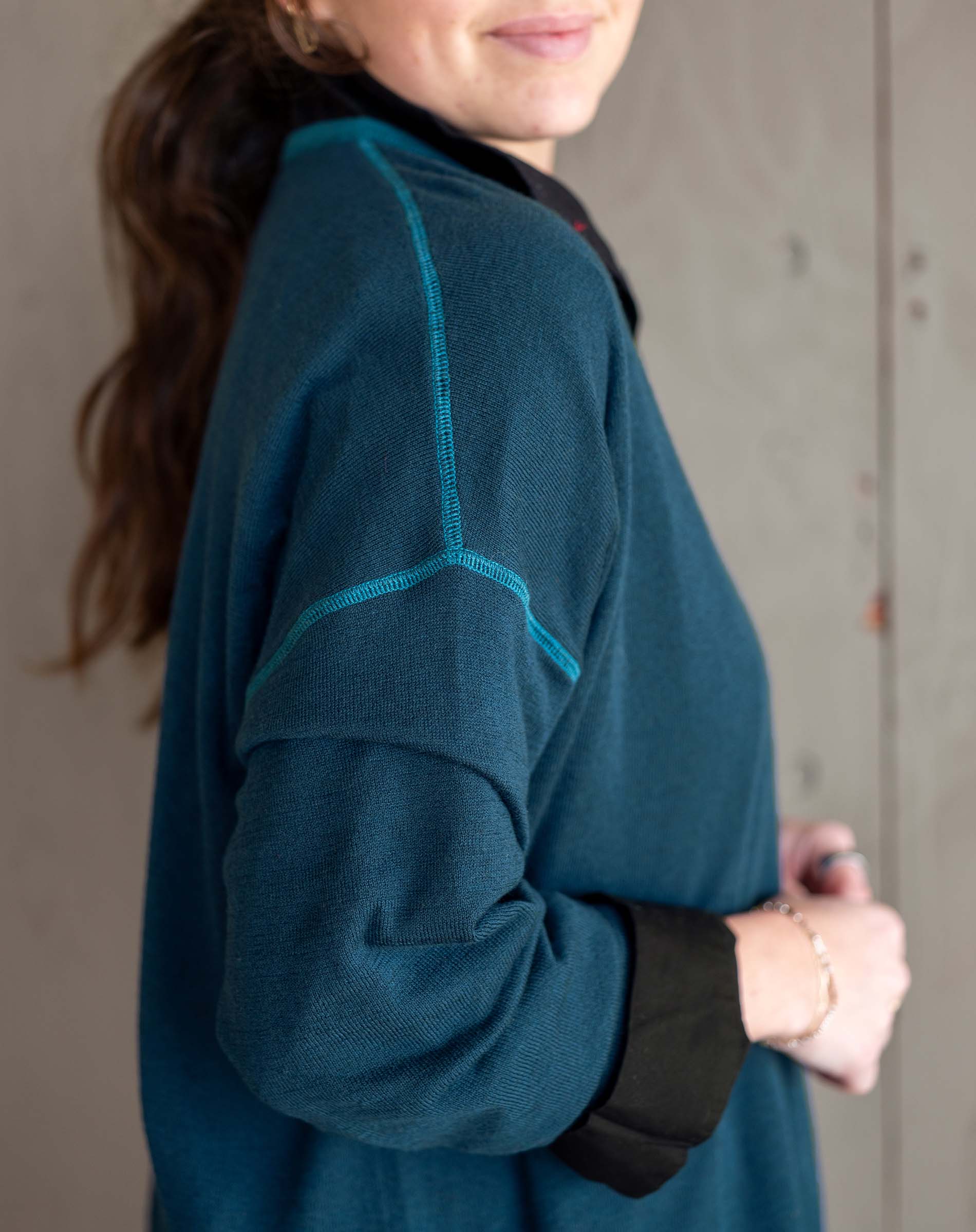 Person wearing a teal fleece jacket with black accents against a neutral background