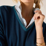 Deep teal v-neck knit top over a white button-down shirt.