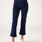 lower body of Woman showcasing Mersea moody blue Nomad cropped mini boot-cut jeans against white background