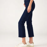 lower body side view of Woman showcasing Mersea moody blue Nomad cropped mini boot-cut jeans standing on white background