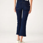 lower body rear view of Woman wearing Mersea Moody blue Nomad cropped mini boot-cut jeans standing on white background