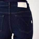 closeup rear view of Woman wearing Mersea Moody blue Nomad cropped mini boot-cut jeans standing against white background