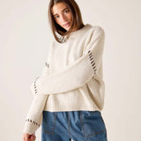 Cream knit whipstitch sweater with textured weave and statement stitching on the sleeves.