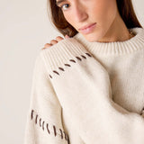 Cream knit sweater with whipstitch detail on the sleeves.