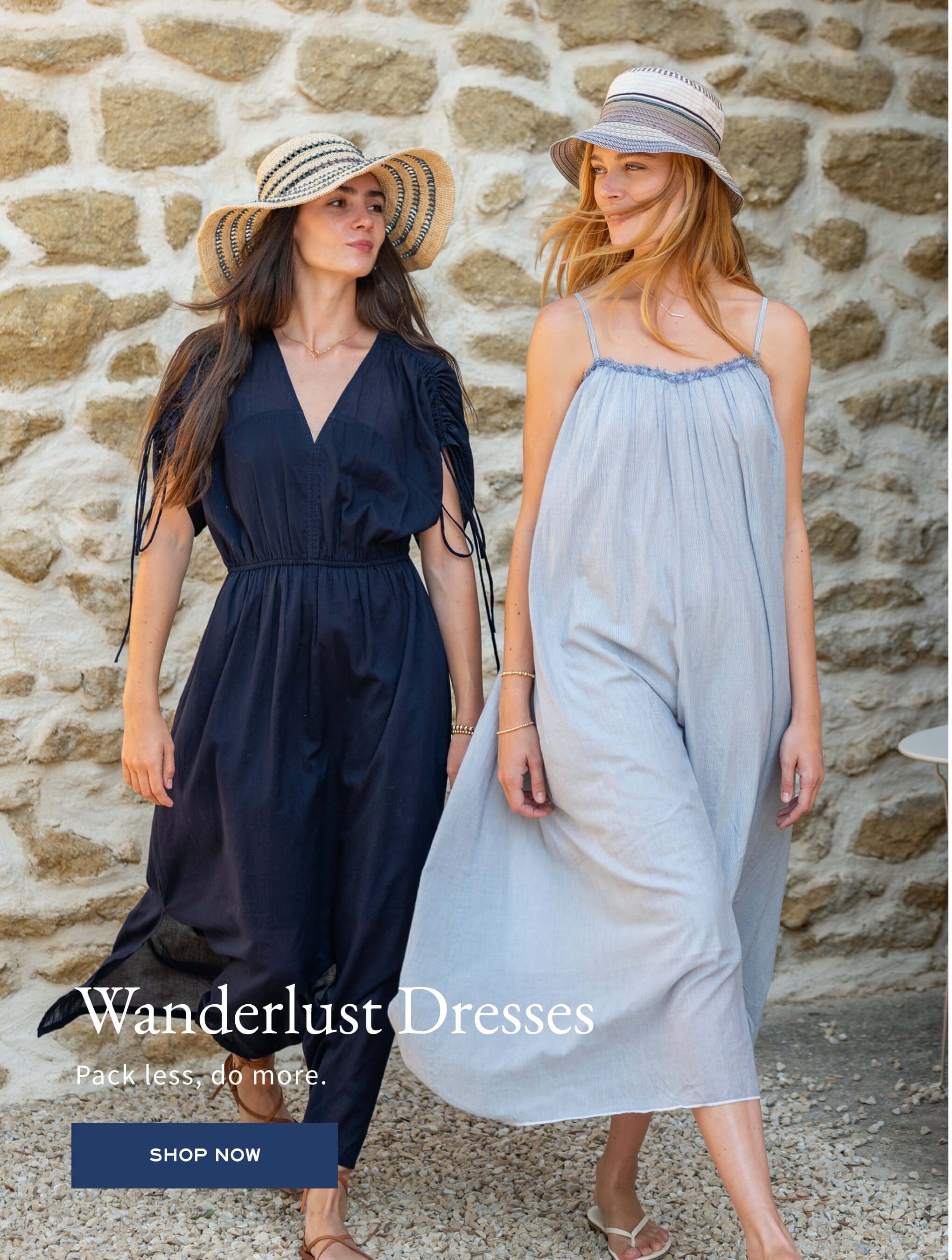 Two women wearing dresses and hats against a stone wall, with 'Wanderlust Dresses' branding.