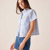Woman wearing a blue and white striped shirt with a plain background