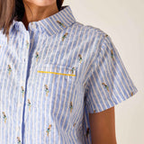 Close-up of a person wearing a blue and white striped shirt with small patterns on a plain background