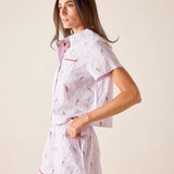 Woman wearing a white pajama set with red accents on a beige background