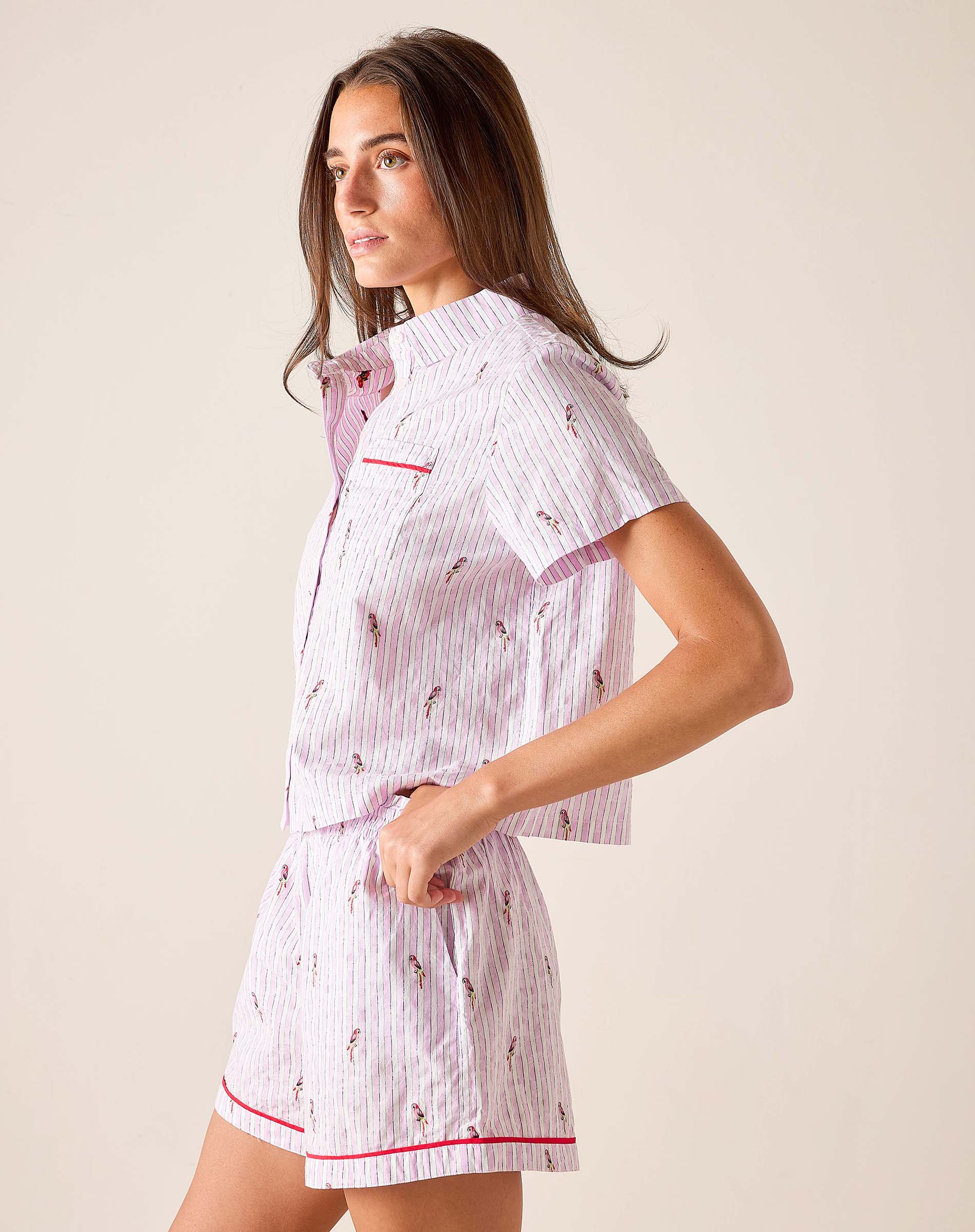 Woman wearing a white pajama set with red accents on a beige background