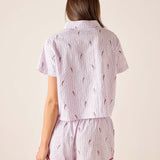 Woman wearing a pink and white striped pajama set with a subtle pattern on a beige background