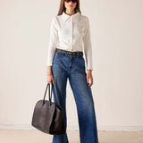 MERSEA women's travel-friendly ladies' travel-ready white ribbed oxford button-down shirt paired with high-waisted wide-leg denim jeans.