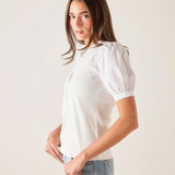 Woman wearing a white blouse with puffed sleeves against a plain background
